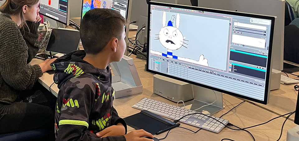 Student viewing an illustration of a rabbit on a computer screen in a classroom.