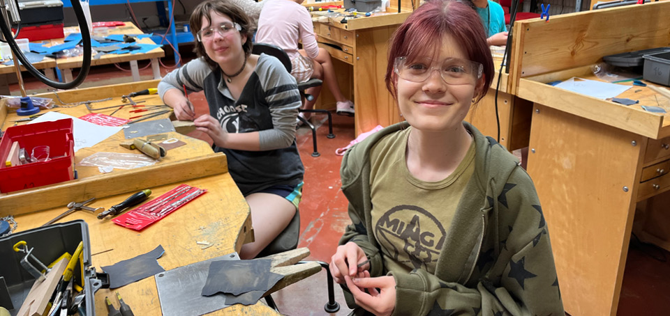 Smiling students at their workstations as they make jewelry